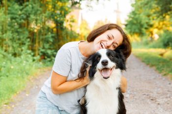 smiling woman hugging her dog in the part