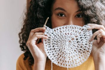 Woman smiling and doing crochet
