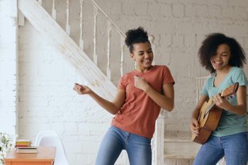 two young woman dancing and playing guitar